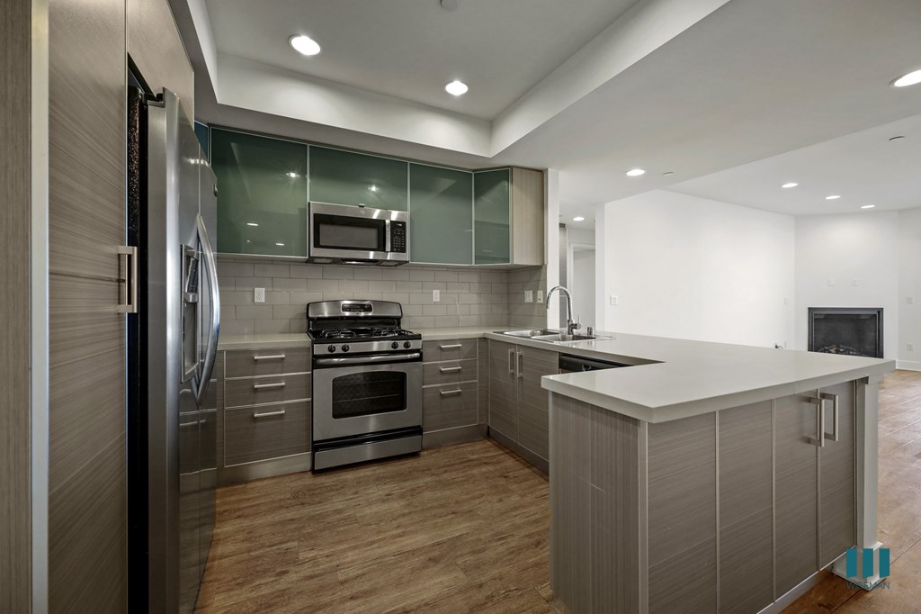 A modern kitchen with stainless steel appliances and wooden floors.