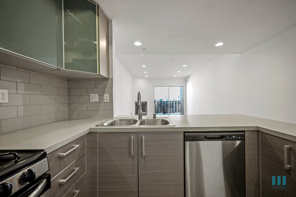 A modern kitchen with a stainless steel dishwasher and a black stove top.