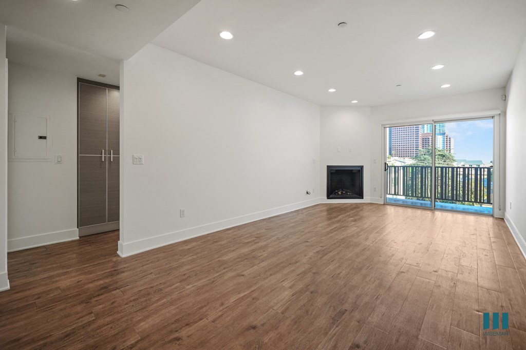 A spacious room with wooden flooring and a balcony with a railing.
