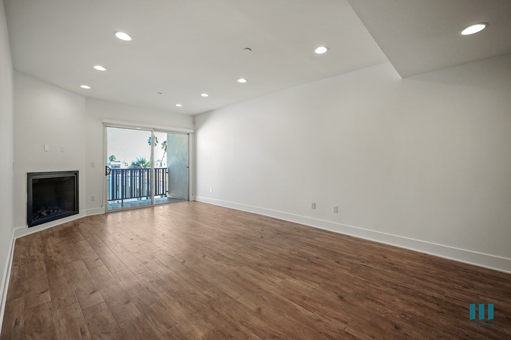 A spacious room with wooden flooring and a fireplace.