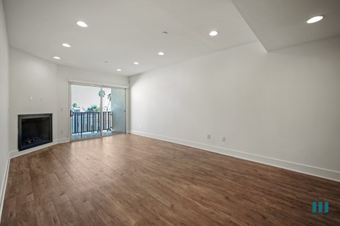 A spacious room with wooden flooring and a fireplace.