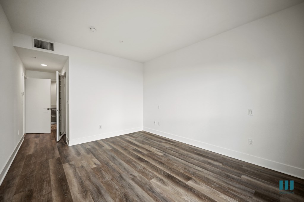 A room with wooden flooring and white walls.