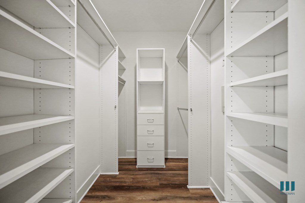 A walk-in closet with white shelving and drawers.