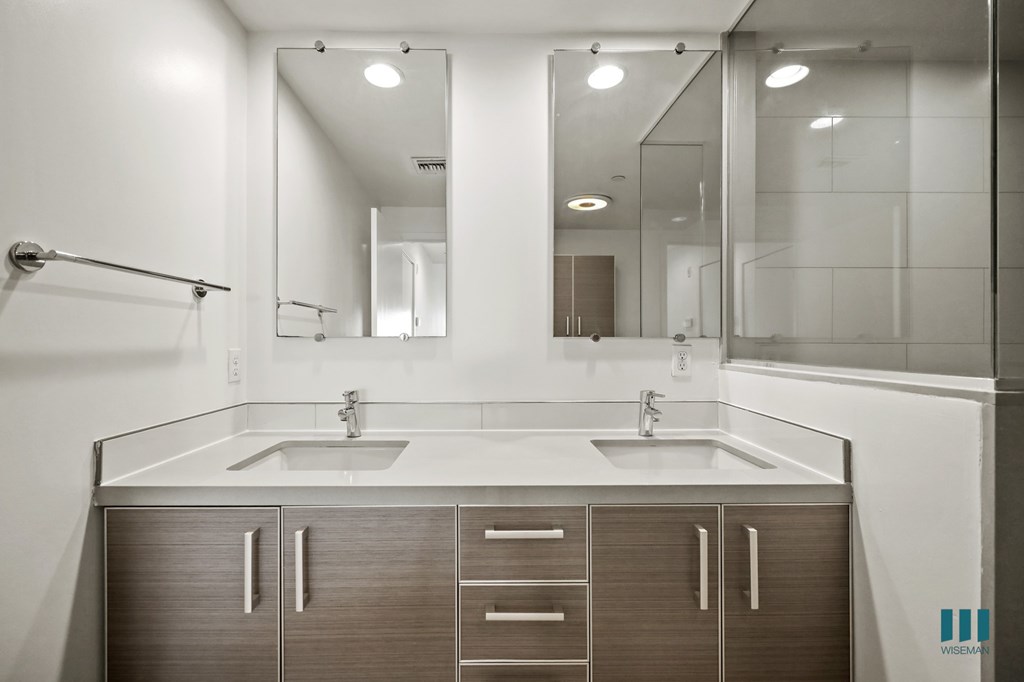 A modern bathroom with a double sink vanity and a large mirror.