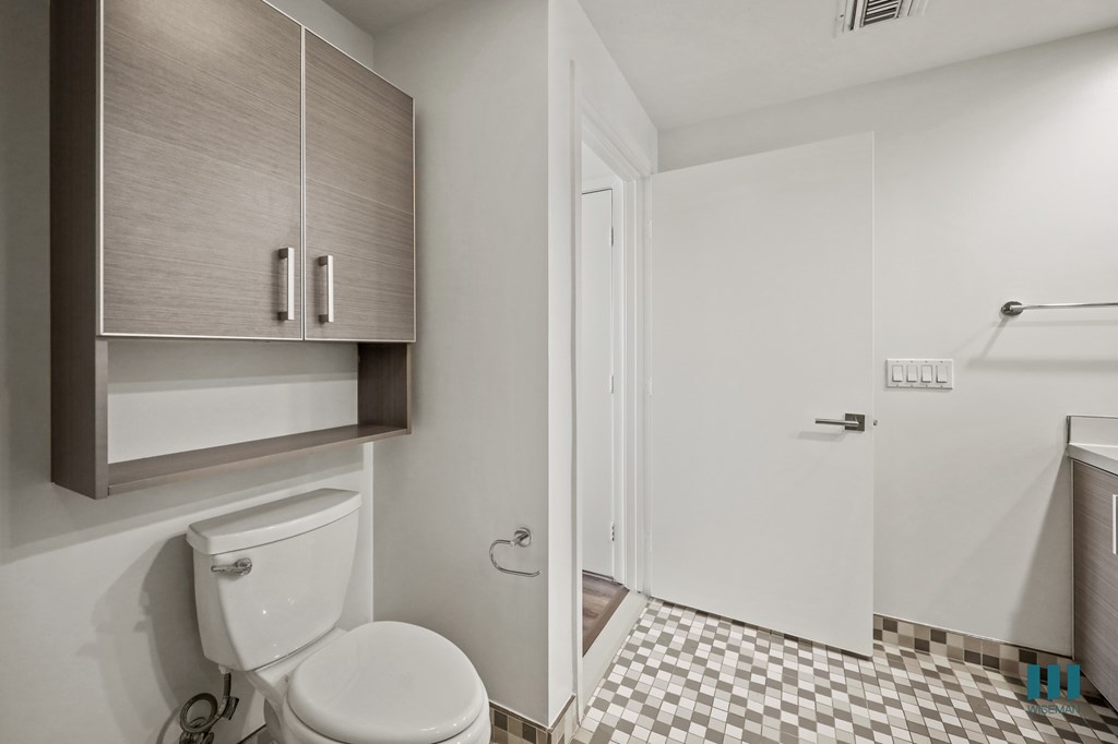 A white toilet is in a small bathroom with a checkered floor.