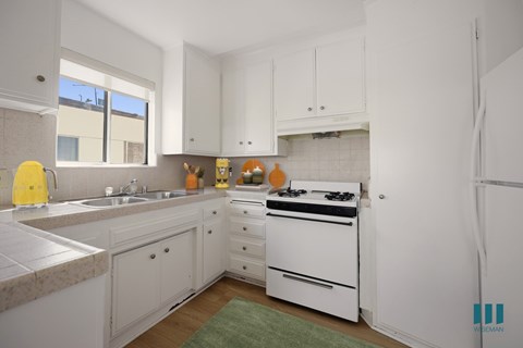 A kitchen with white cabinets and a white stove.