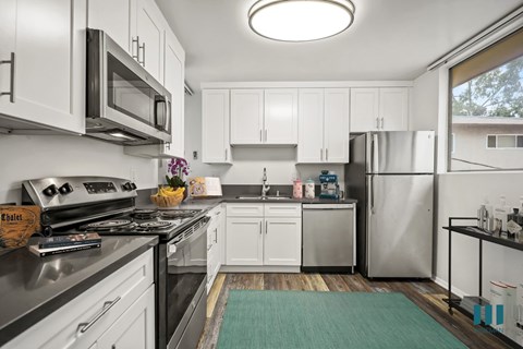 A modern kitchen with white cabinets and stainless steel appliances.