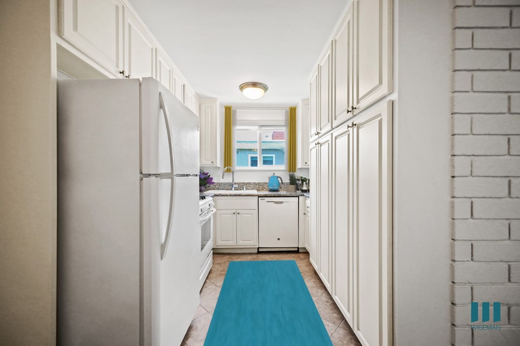 A kitchen with white cabinets and a white fridge.
