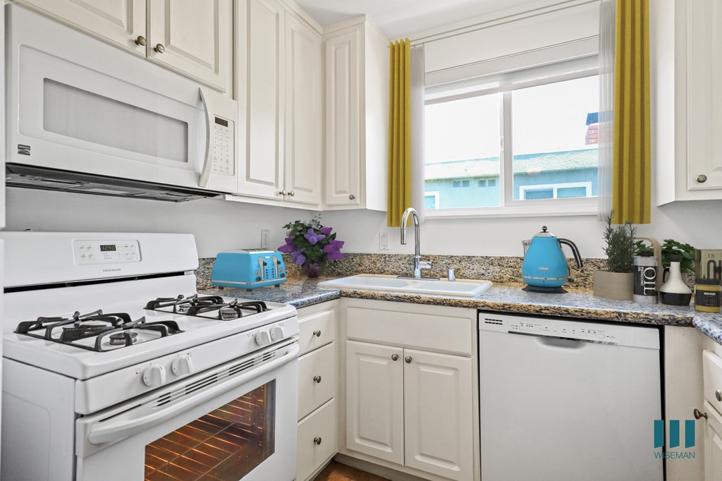 A kitchen with white appliances and cabinets.