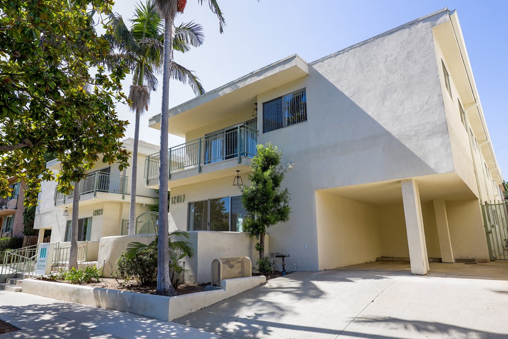 the exterior of a yellow and white building with palm trees