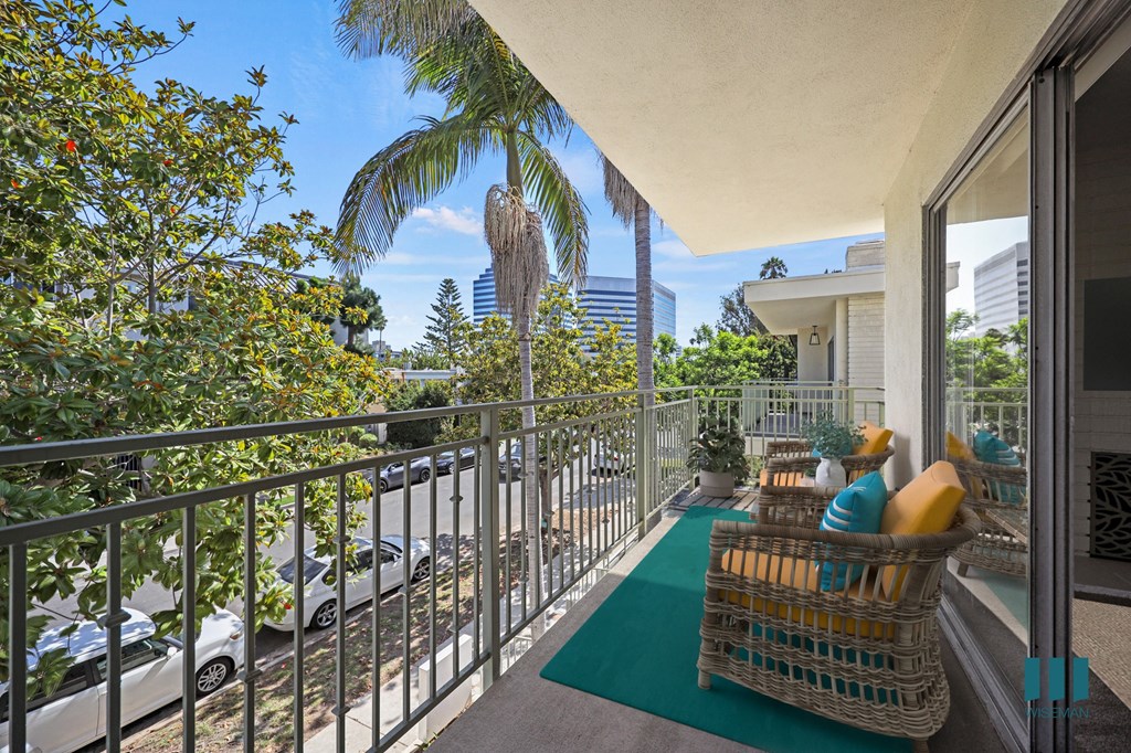 a condo balcony with a chair and a palm tree