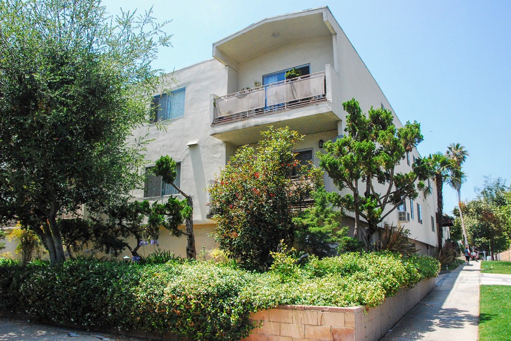 A white two-story building with a balcony on the second floor.