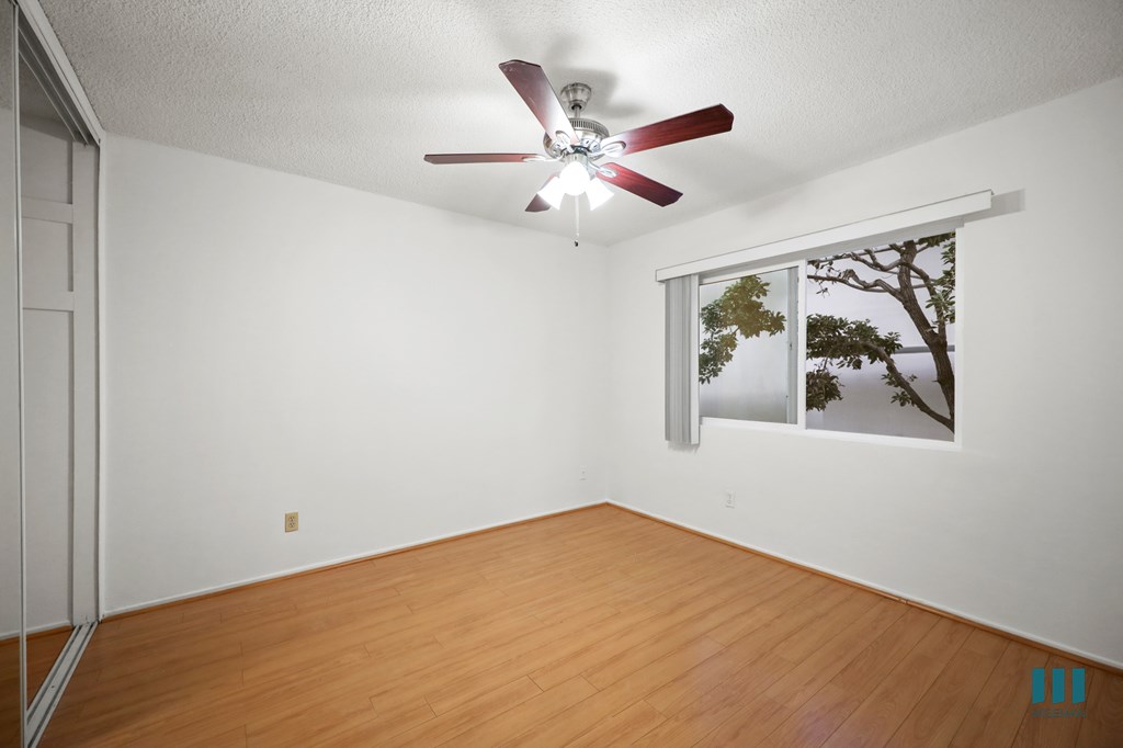 Bedroom with Mirrored Closet, Vinyl Flooring, Ceiling Fan, and Windows
