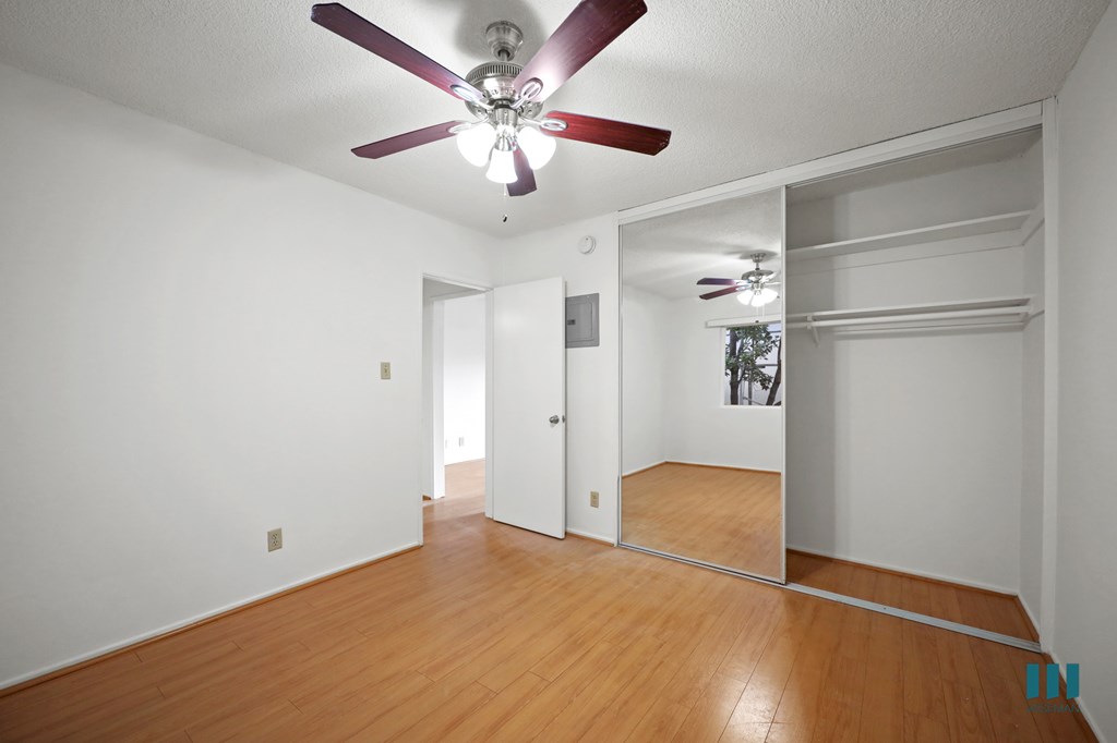 Bedroom with a Mirrored Closet, Ceiling Fan, and Vinyl Flooring
