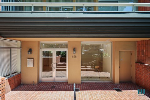 The image shows a building entrance with a glass door and a number 818 on it.