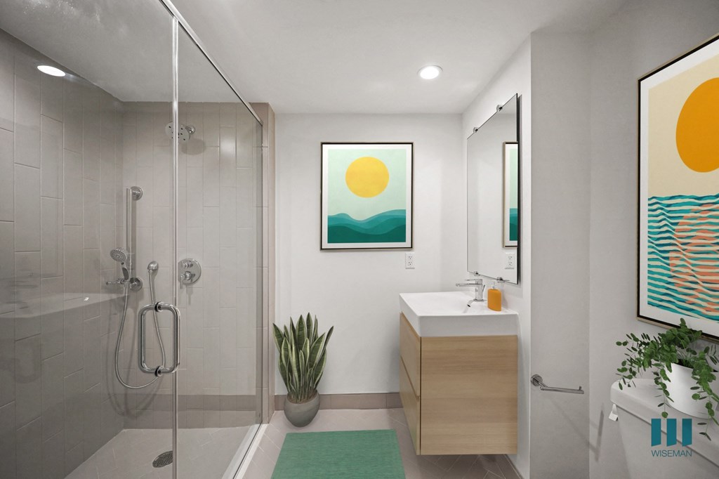 A bathroom with a shower, sink, and two framed pictures on the wall.