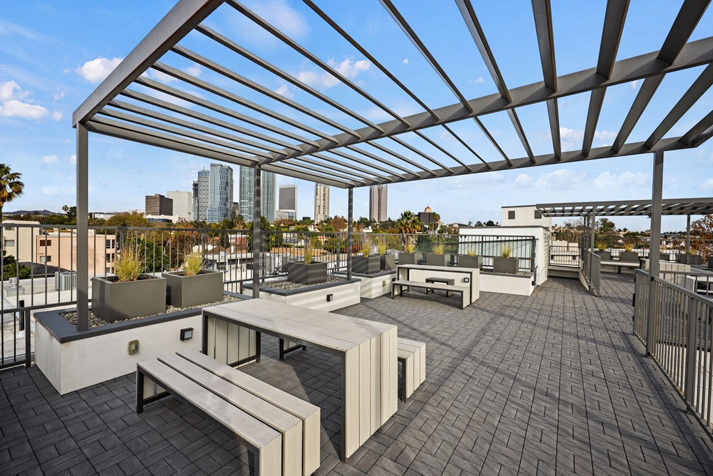 A rooftop patio with a metal pergola and benches.