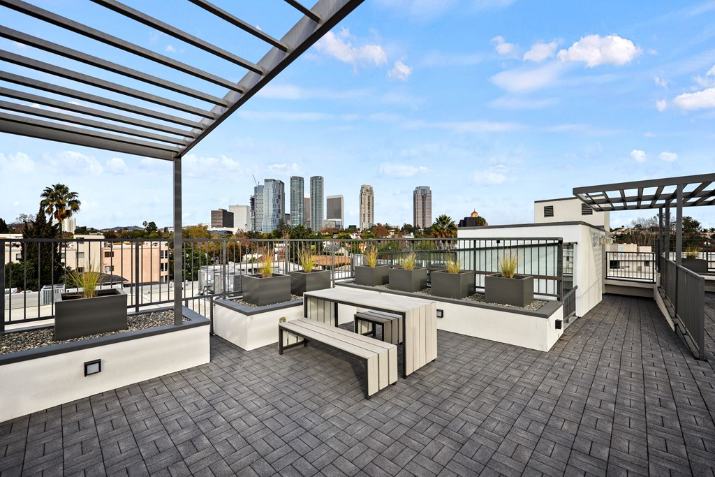 A rooftop patio with a bench and a table.