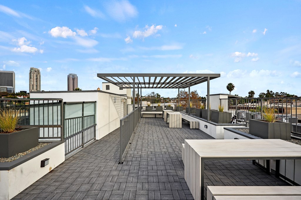 A rooftop patio with a long table and chairs under a canopy.