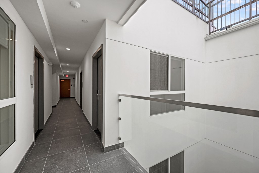A long hallway with a skylight and a white wall on the side.