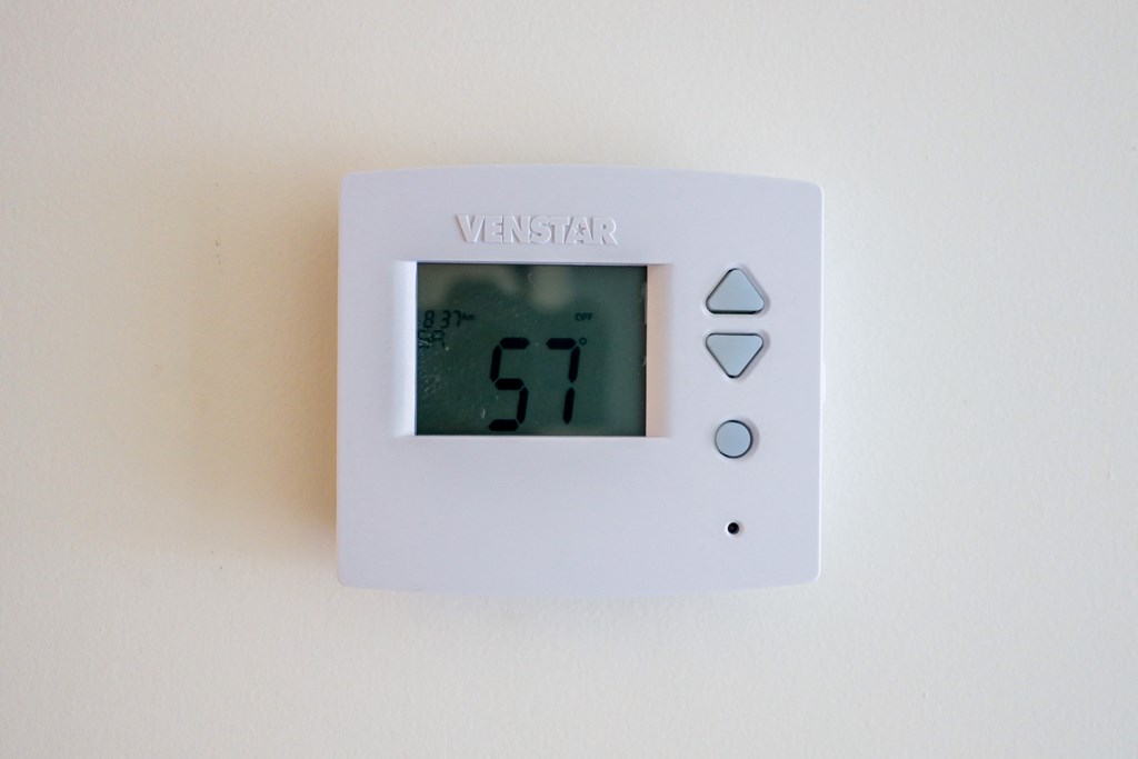 A white thermostat with the number 57 on the screen.