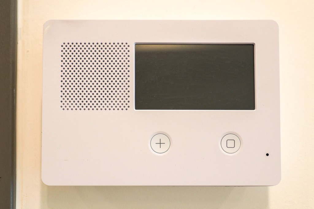 A white device with a black screen and a speaker on the left.
