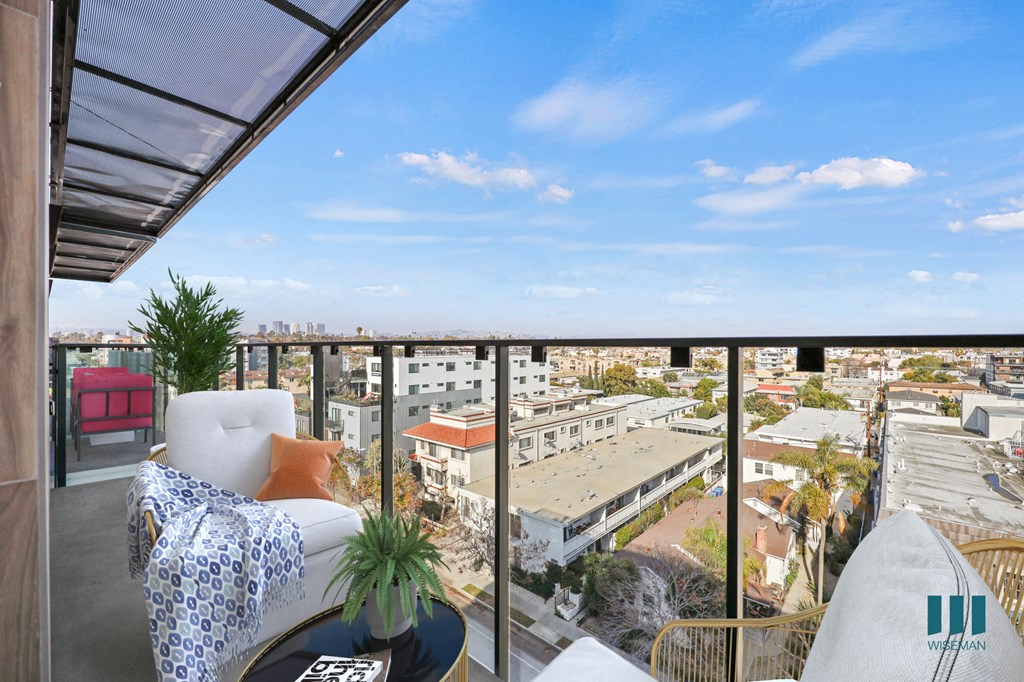 A balcony with a couch and a plant on it overlooks a cityscape.