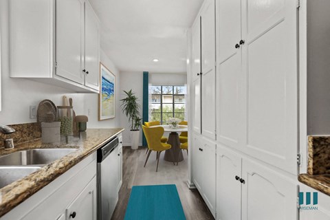 a kitchen with white cabinets and a dining room with a window