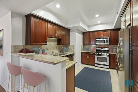 a kitchen with wood cabinets and granite counter tops and a island with pink chairs