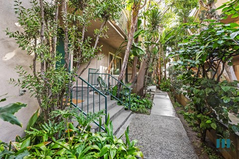 A pathway with a metal railing on the left side and a building in the background.