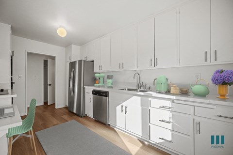 A kitchen with white cabinets and a green chair.