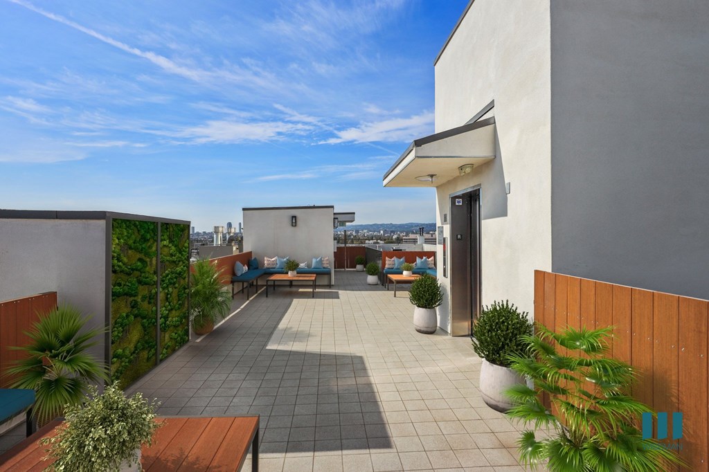 A patio with a table and chairs is surrounded by a green wall.