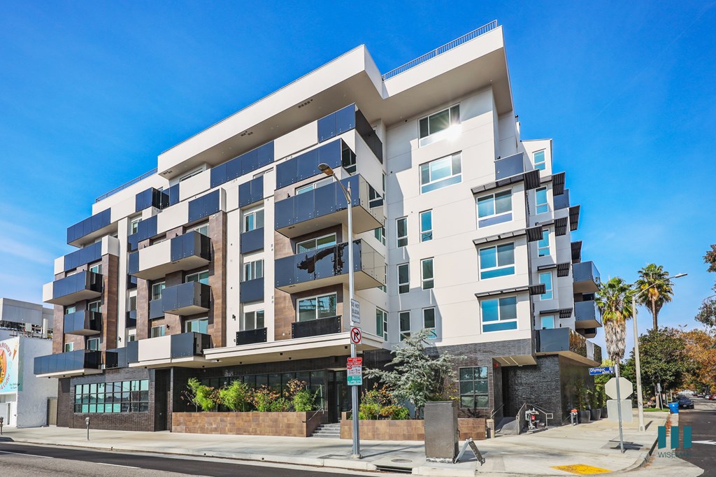 A modern multi-story building with a flat roof and balconies.