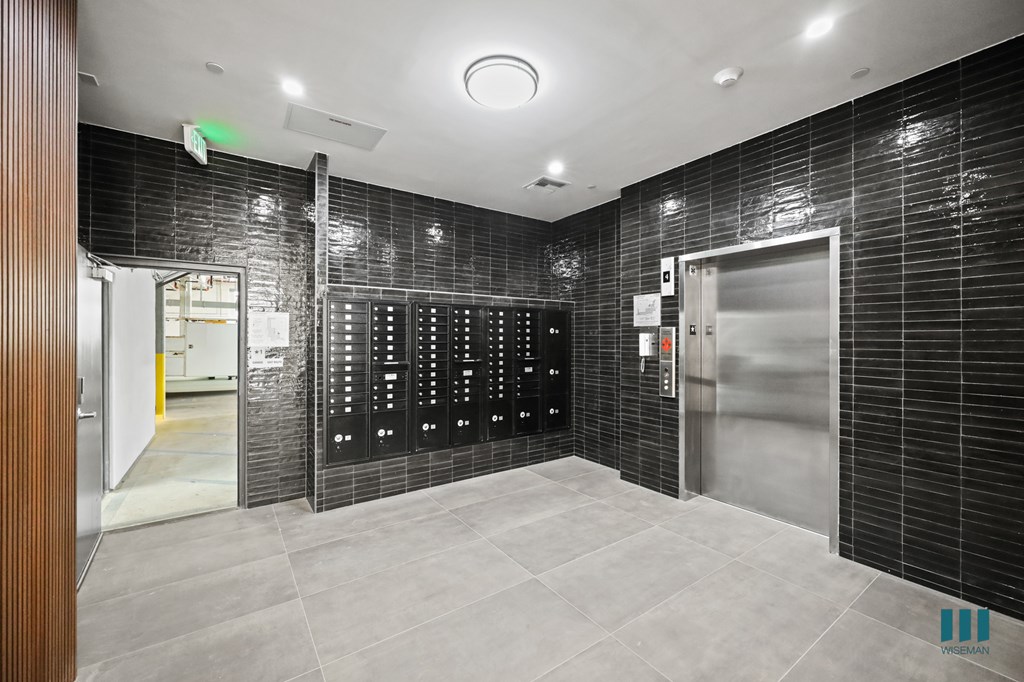 A room with a black tiled wall and a row of lockers.