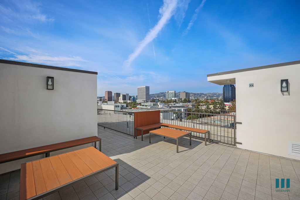 A balcony with two benches and a table with a view of the city.
