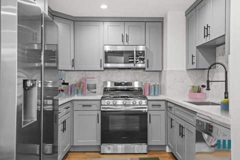 A modern kitchen with a stainless steel refrigerator and a black stove top oven.