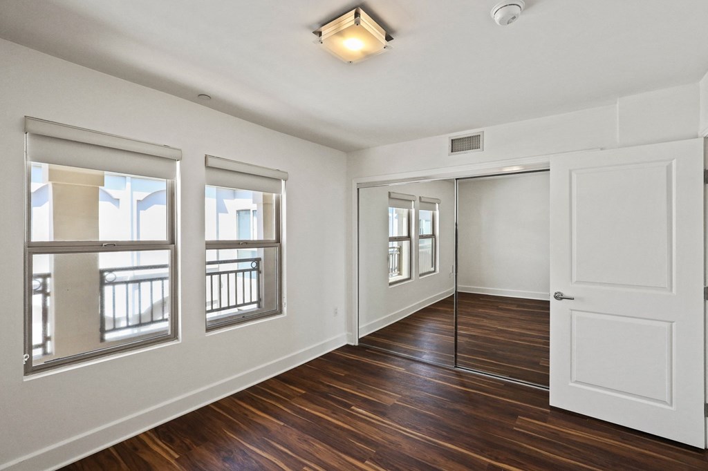 Bedroom with Mirrored Closet, Vinyl Flooring, and Double Windows