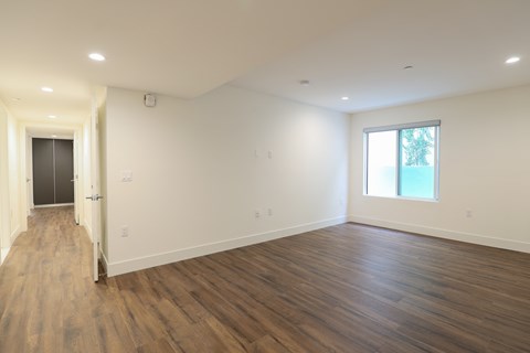 a living room with white walls and wooden floors and a window