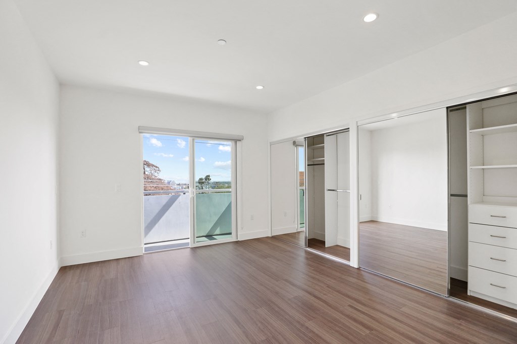 Large-Size Bedroom with Two Closets with Built-In Organizers, Balcony, Recessed Lighting, and Vinyl Flooring