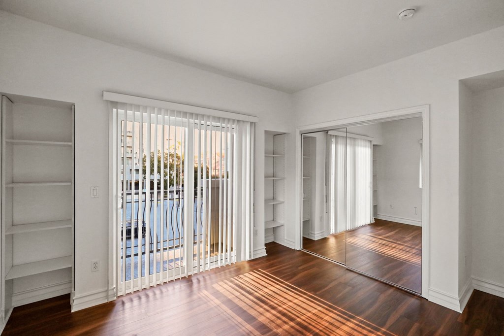 Bedroom with Mirrored Closet, Built-In Shelving, and Balcony