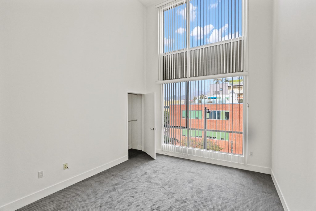 Spacious Bedroom with High Ceilings and Window Views