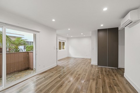 Living Room Area with Vinyl Flooring, Wall Heater, and Sliding Glass Door to Access Patio