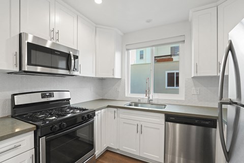 a kitchen with white cabinets and stainless steel appliances