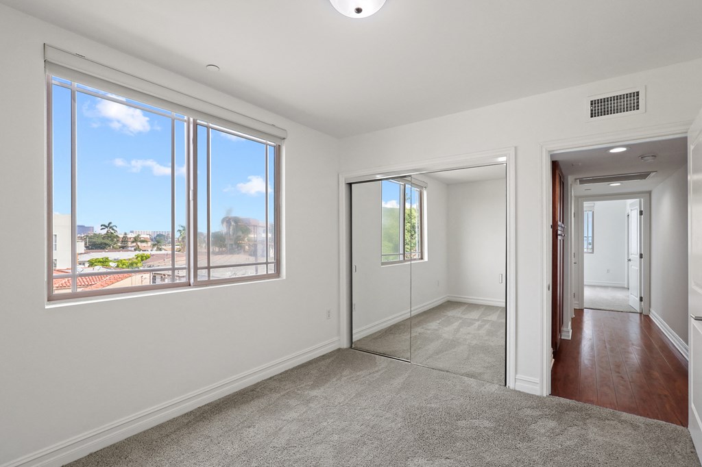 Bedroom with a Carpet, Window, and a Mirrored Closet