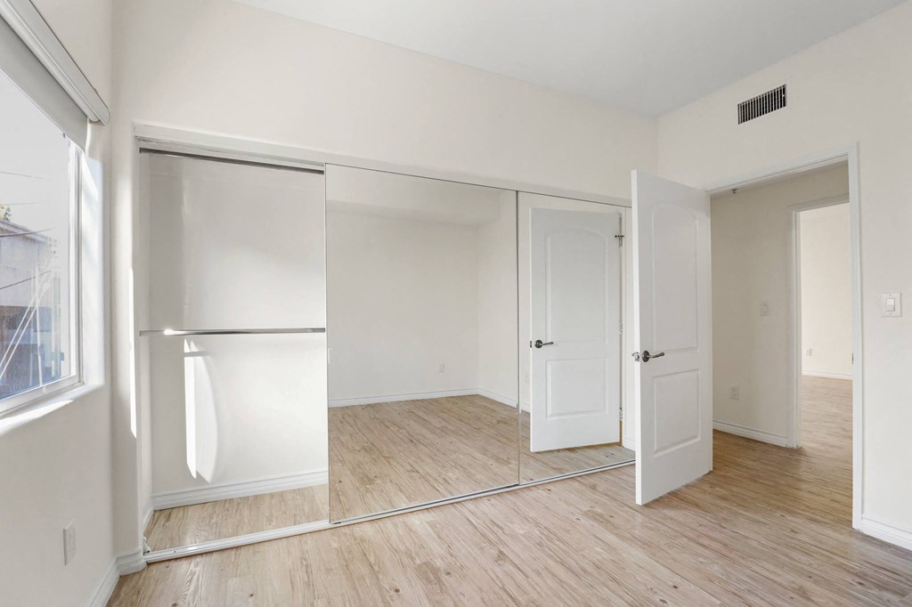 Large Bedroom with Full-Size Mirrored Closet, Vinyl Flooring, and Window
