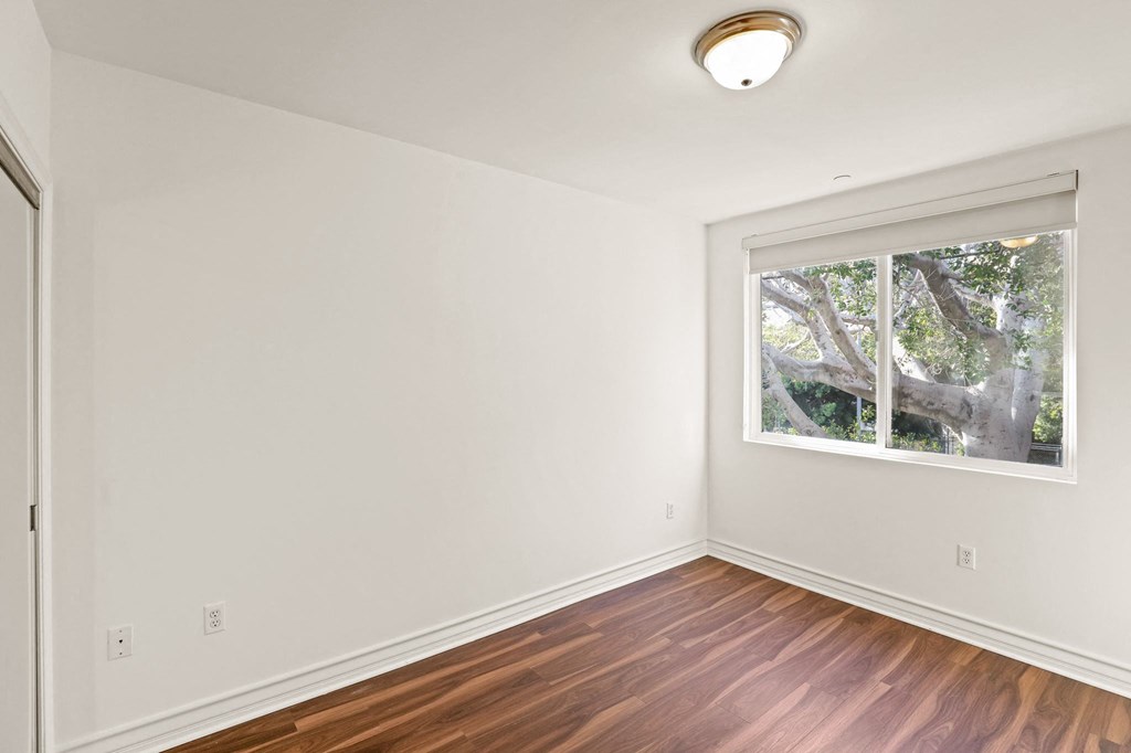 Bedroom with Mirrored Closet, Large Window, and Vinyl Flooring