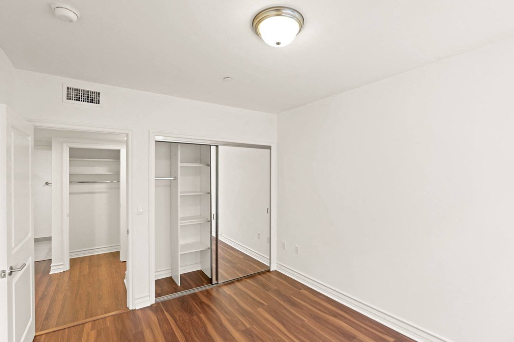 Bedroom with Mirrored Closet and Hardwood Flooring