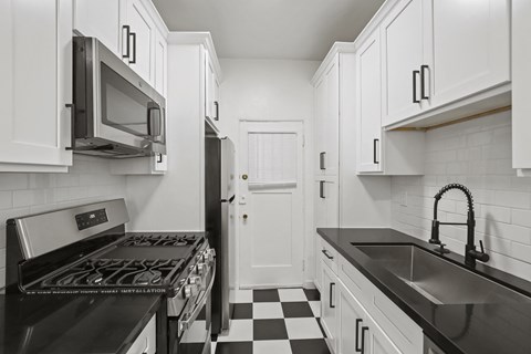 a kitchen with white cabinets and a black and white checkered floor
