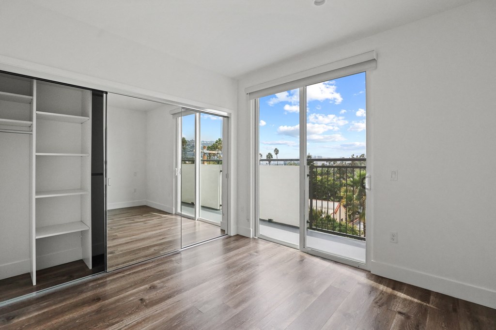 Bedroom with Large-Size Mirrored Closet with Shelving, Vinyl Flooring, and Balcony
