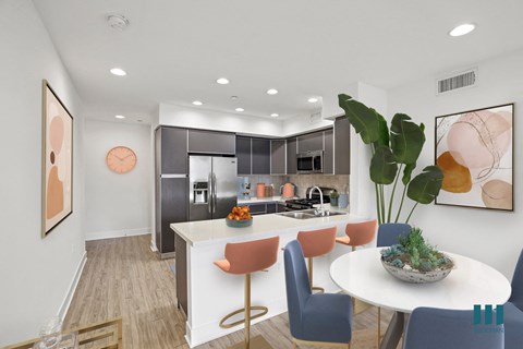 A modern kitchen with a dining table set with chairs and a bowl of plants on the table.